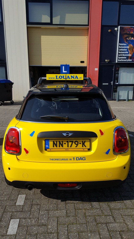 Gele lesauto met rijschoolreclame